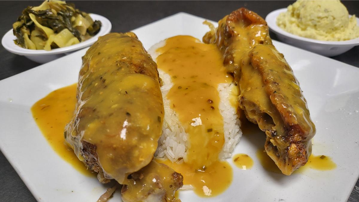 Smothered turkey wings over rice with gravy, collard greens, and potato salad